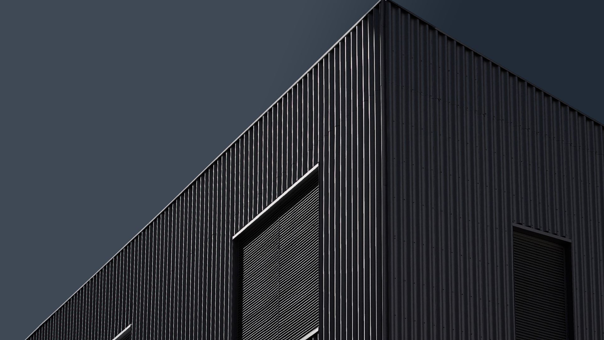 Dark aluminum batten facade catching raking light